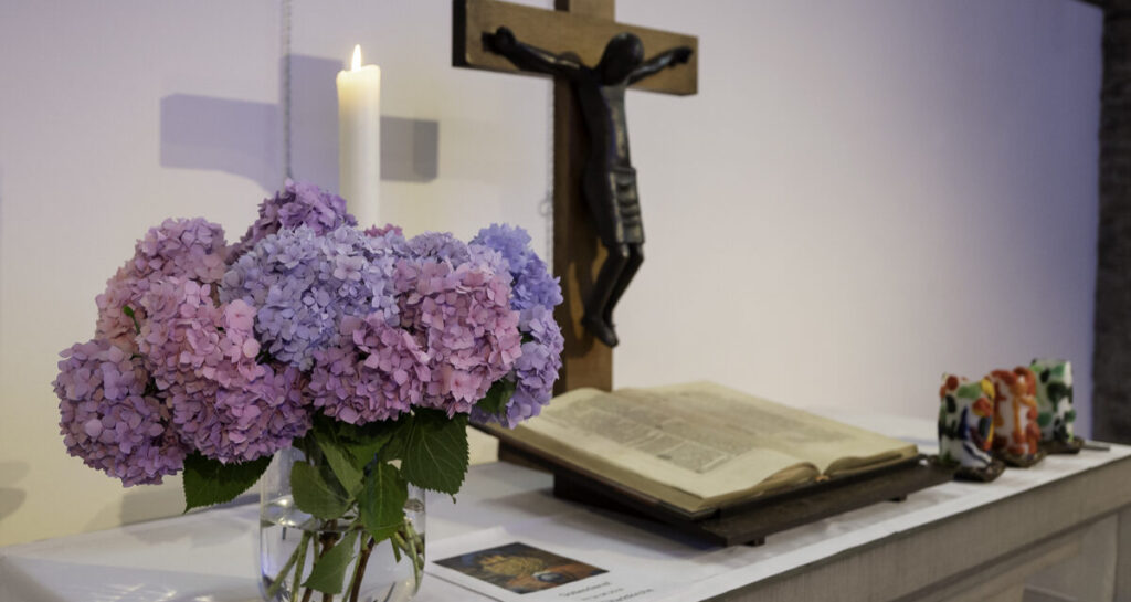 ein mit Blumen geschmückter Altar vor dem Kreuz